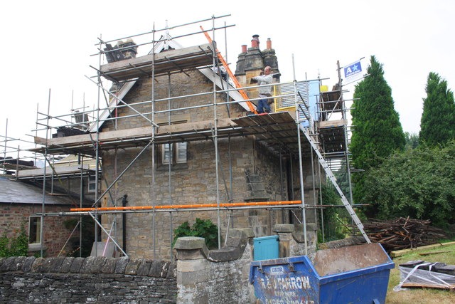 Medium sized stone house being renovated. Scaffolding can be seen covering the house.