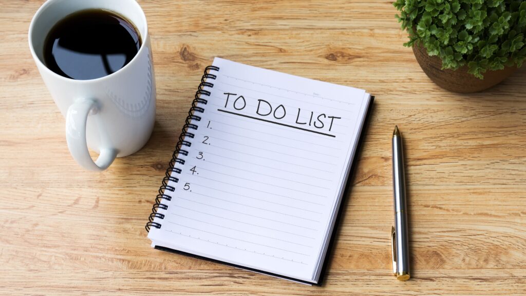 "To do list" written on a notepad with a pen and cup of black coffee