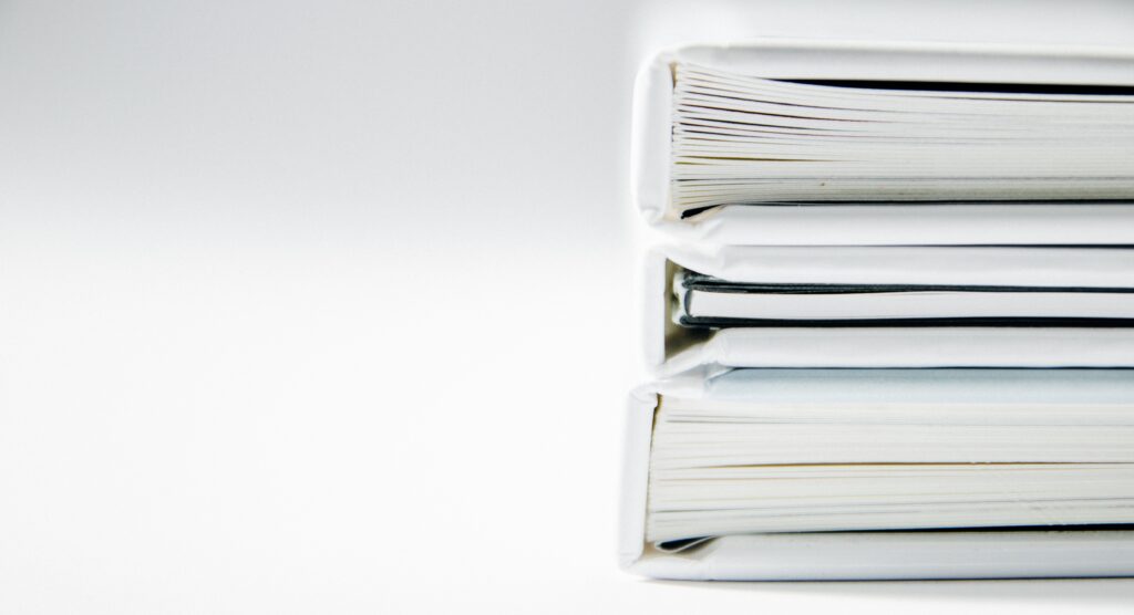 Three white books piled on-top of each other with a white background